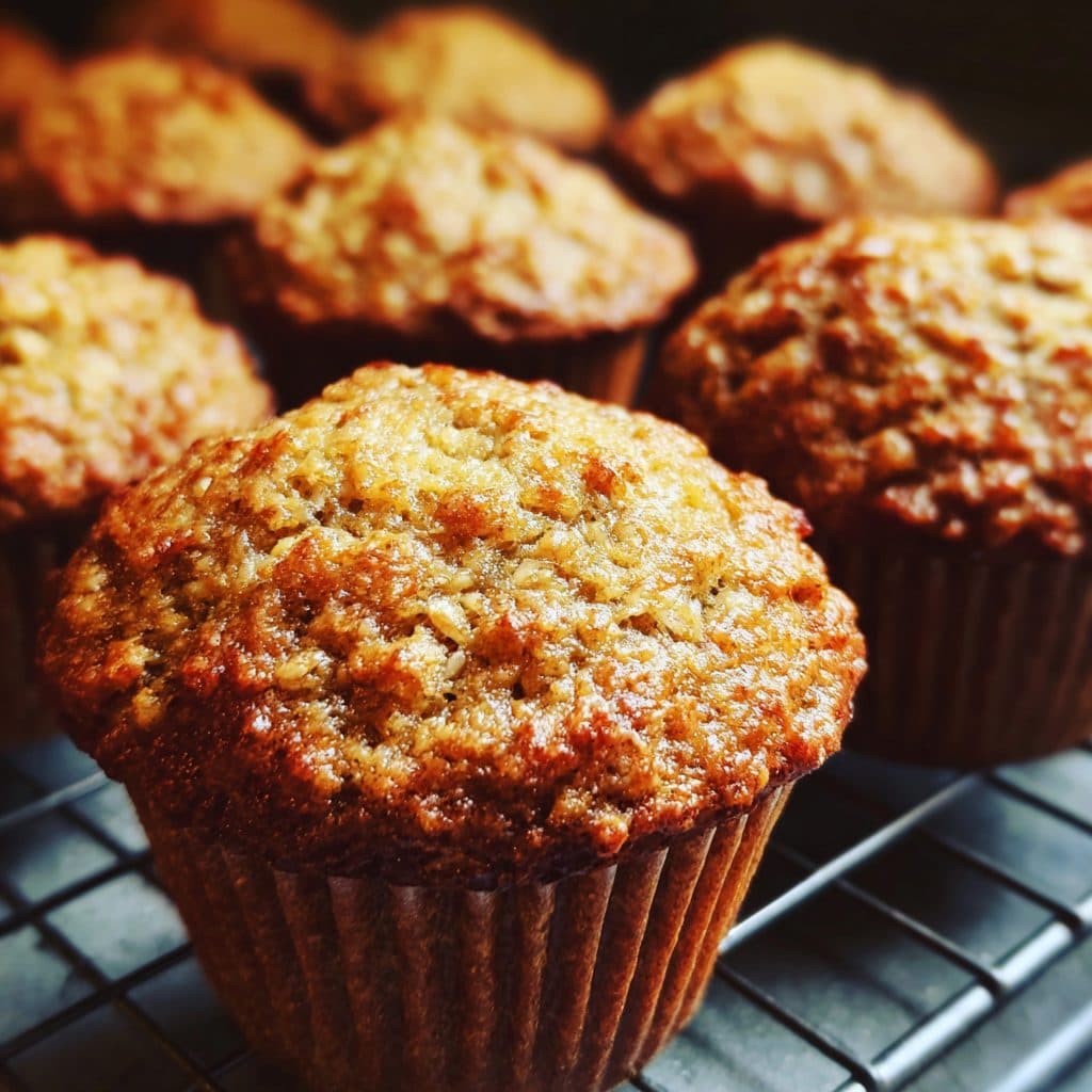 Three gold-brown muffins on a cooling rack.